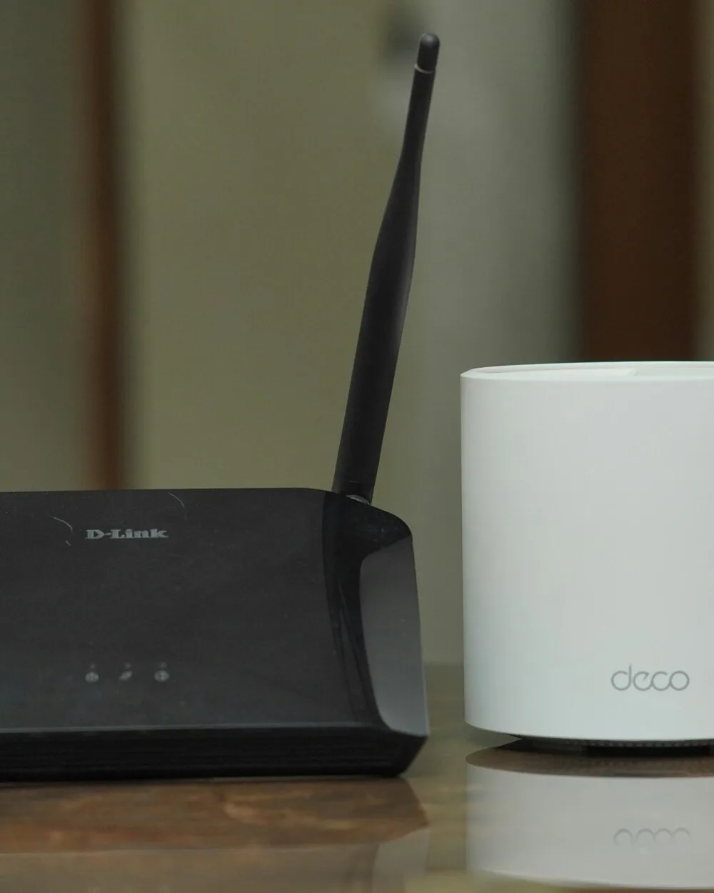 WLAN-Router mit Antennen neben einem runden Mesh-Knoten auf einem Sideboard