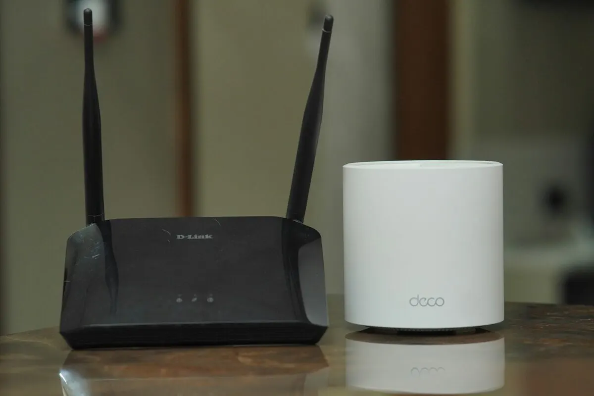 Klassischer WLAN-Router mit Antennen neben einem runden Mesh-Knoten